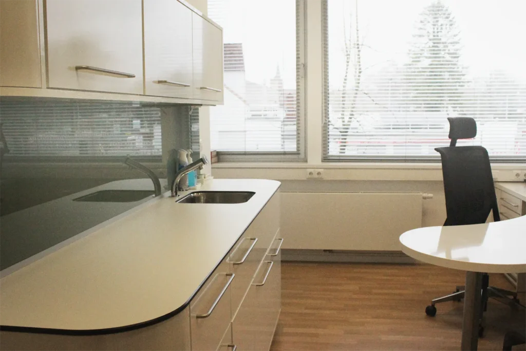 Bild eines der Sprechzimmer, hell, modern und mit Blick nach draußen durch große Fenster.